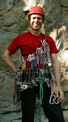 Un grimpeur portant une collection variée de coinceurs mécaniques Un grimpeur portant une collection variée de coinceurs mécaniques