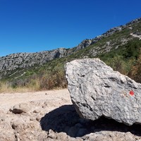 Bloc avec marquage rouge. Le site est au bout de sa pointe gauche, et le sentier à gauche